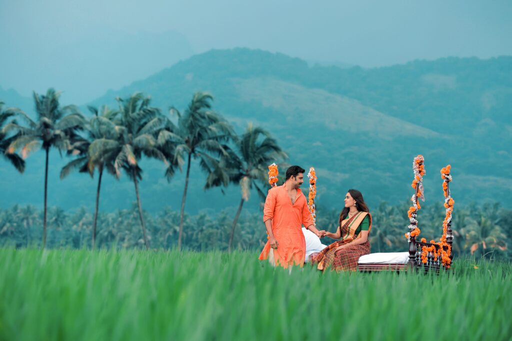 Couple dressed in traditional attire in a lush tropical setting with palm trees and mountains.