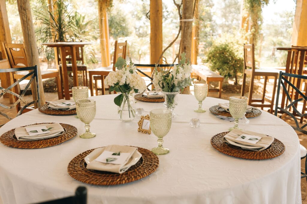 Charming outdoor table setting with floral centerpiece and wicker placemats, perfect for weddings or special occasions.