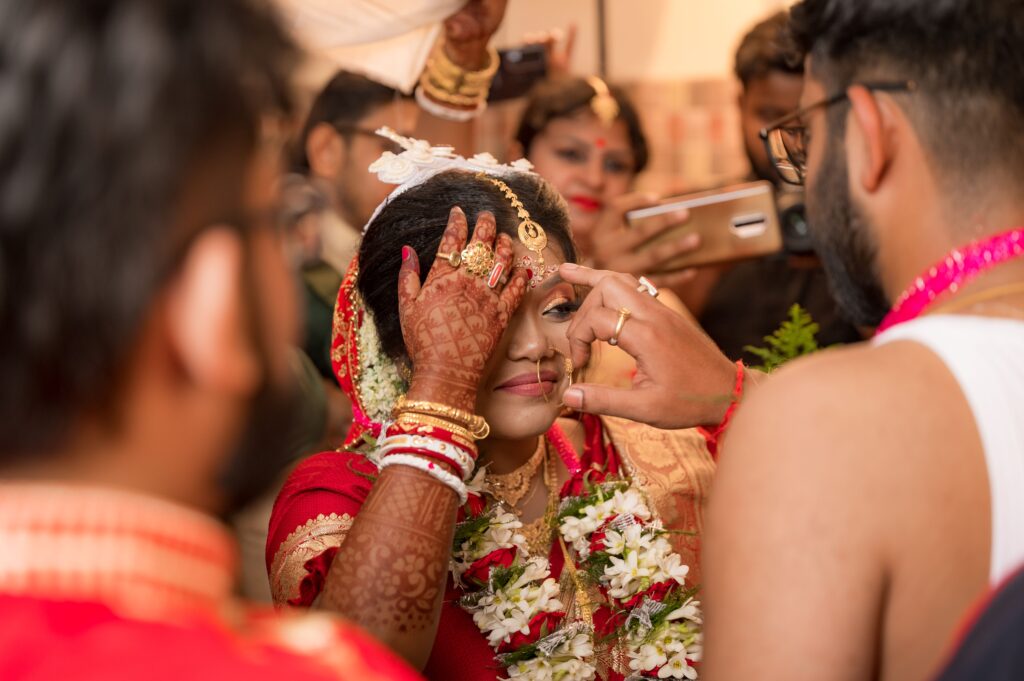 A vibrant Indian bride with henna tattoos during a traditional ceremony, adorned with jewelry.