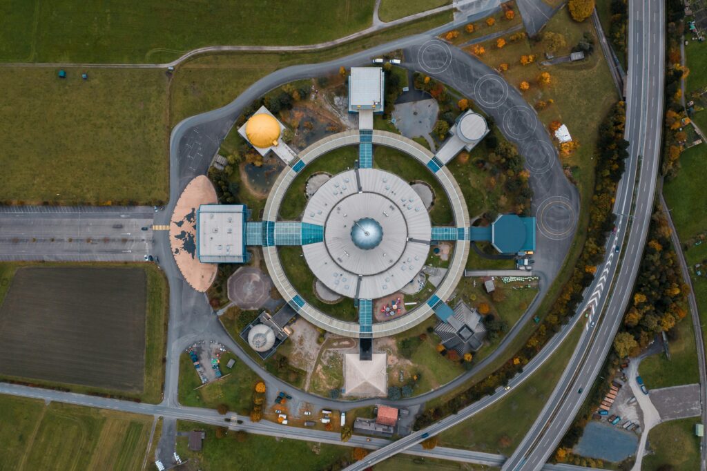 Drone shot capturing a circular building in a countryside setting with surrounding roads.