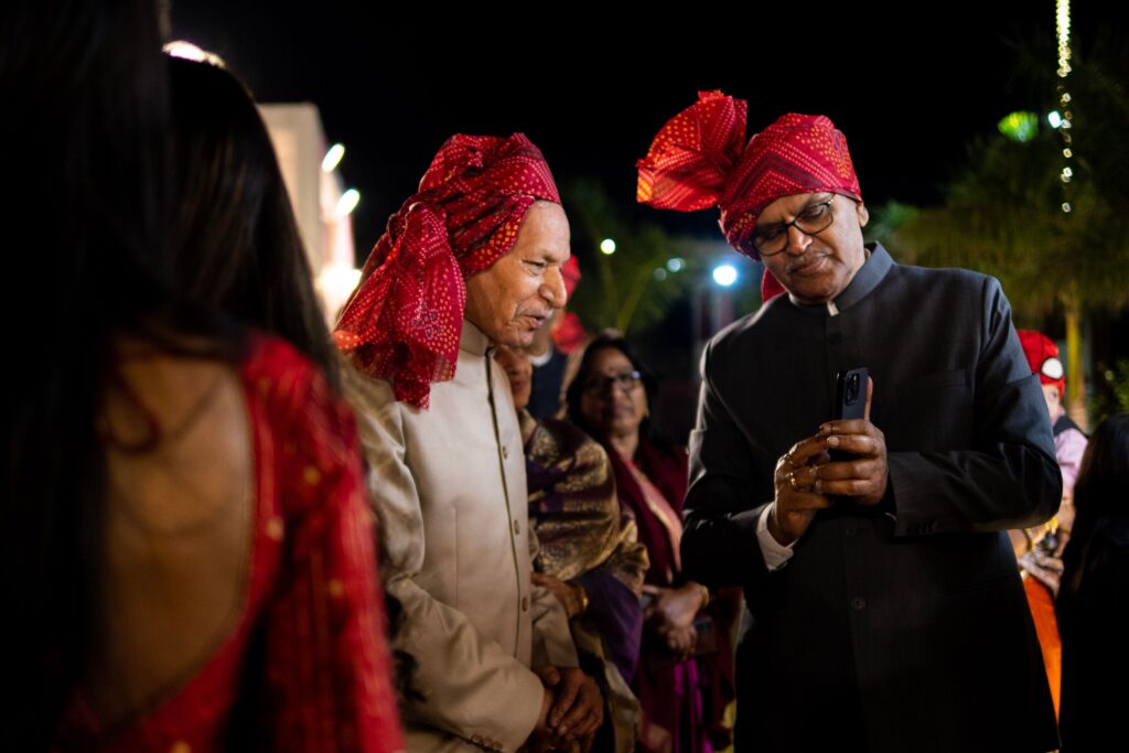 Men in traditional Indian attire and turbans at a night wedding celebration.