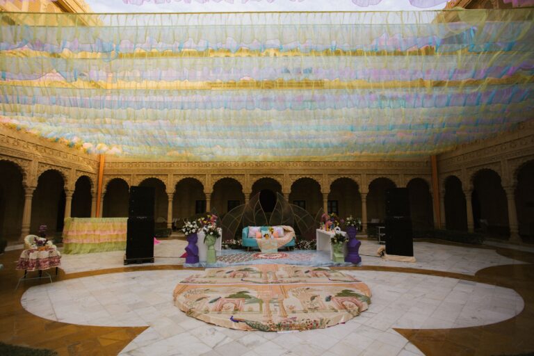 A vibrant outdoor event space with intricate decorations and colorful canopy in a courtyard.