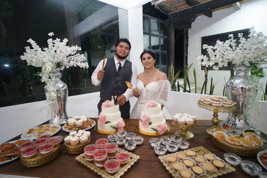 Bride and groom cutting cake at a joyful indoor wedding celebration.