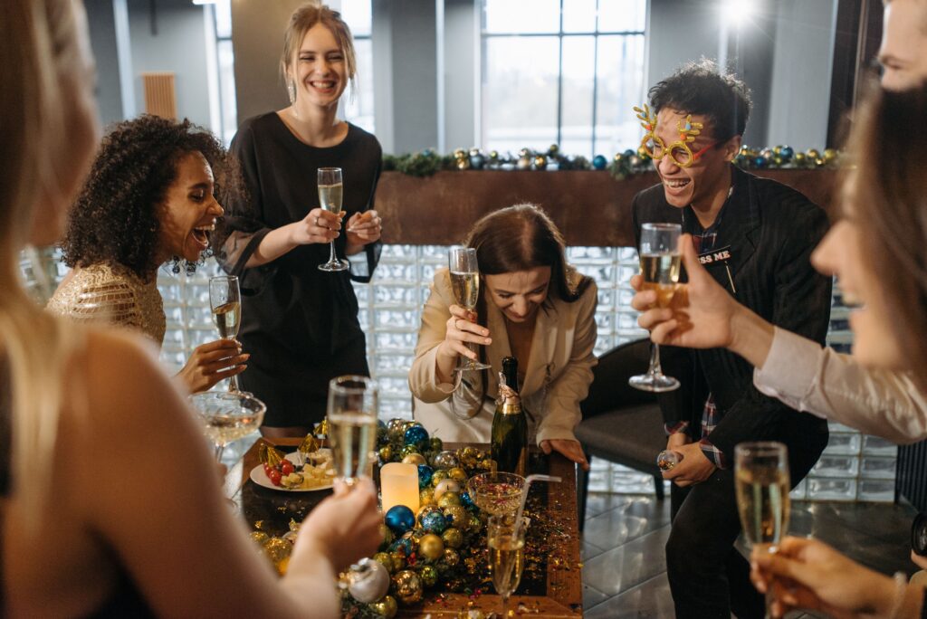 Diverse group of friends joyfully celebrating indoors with champagne and decorations.